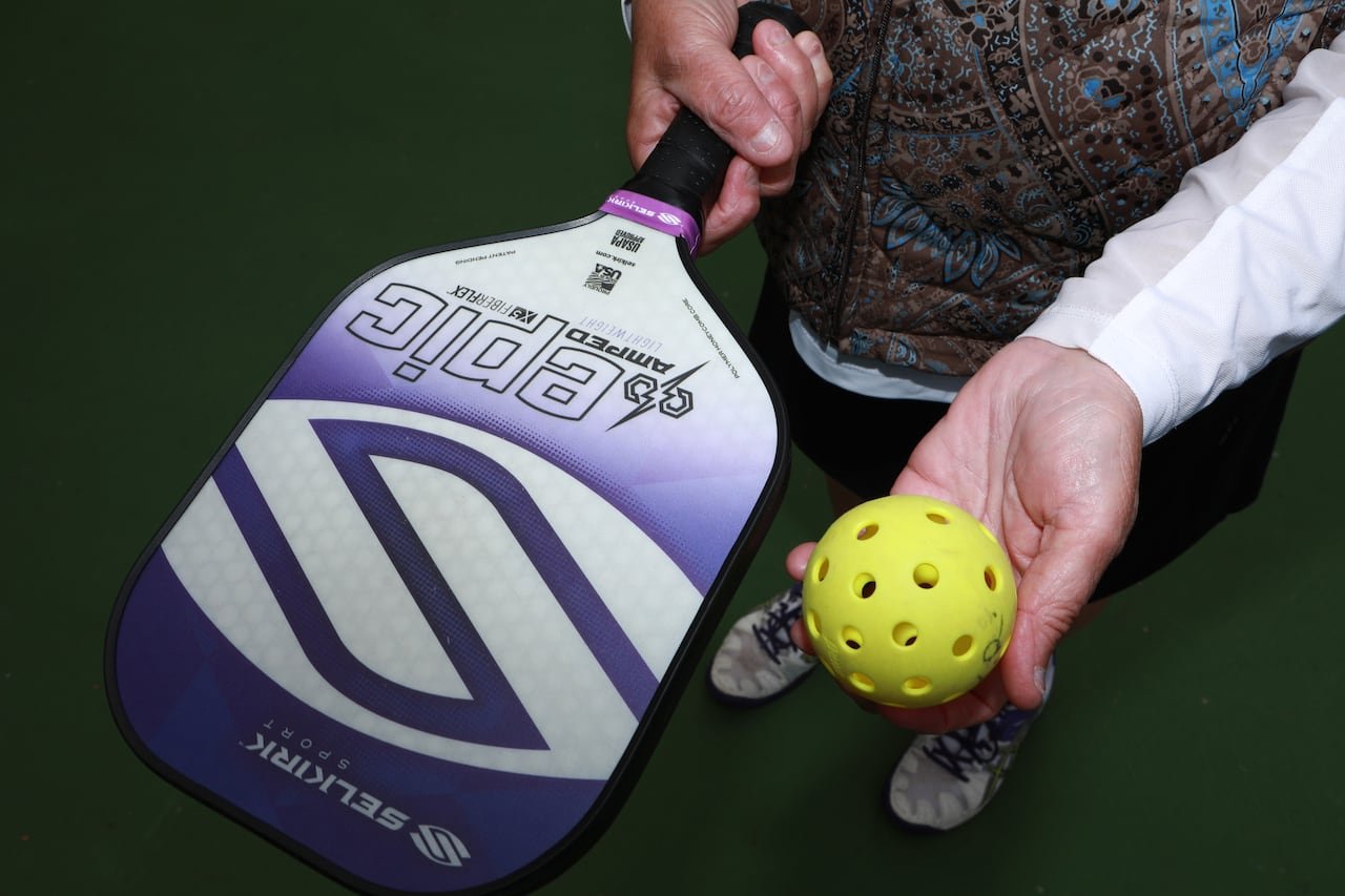 default-1761 Close up photo of a pickleball paddle and ball in a woman's hands.
