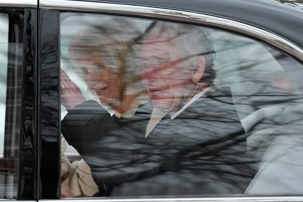 A person waving from inside a car.