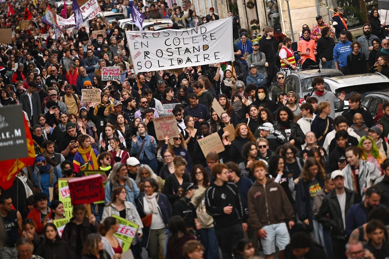 A large crowd of students are seen walking, some holding signs.